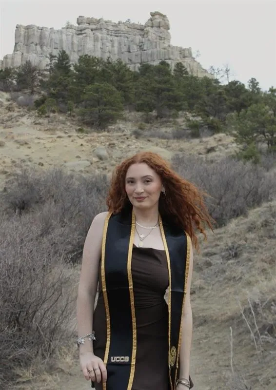 Woman with a black dress and red hair in front of bluffs