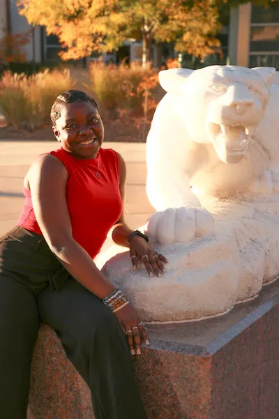 Woman with black hair and red shirt sitting next to mountain lion