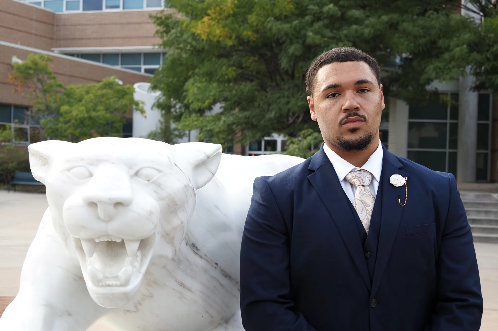 Photo of Ben Moses posing next to a mountain lion statue
