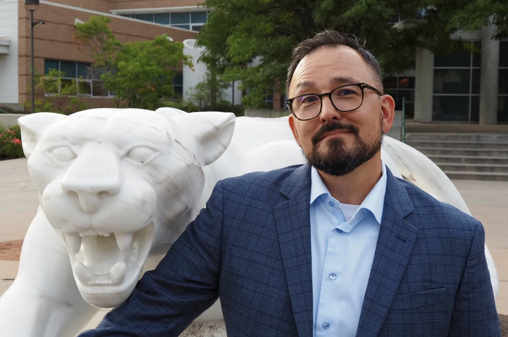 Photo of David Perkins posing next to a mountain lion statue