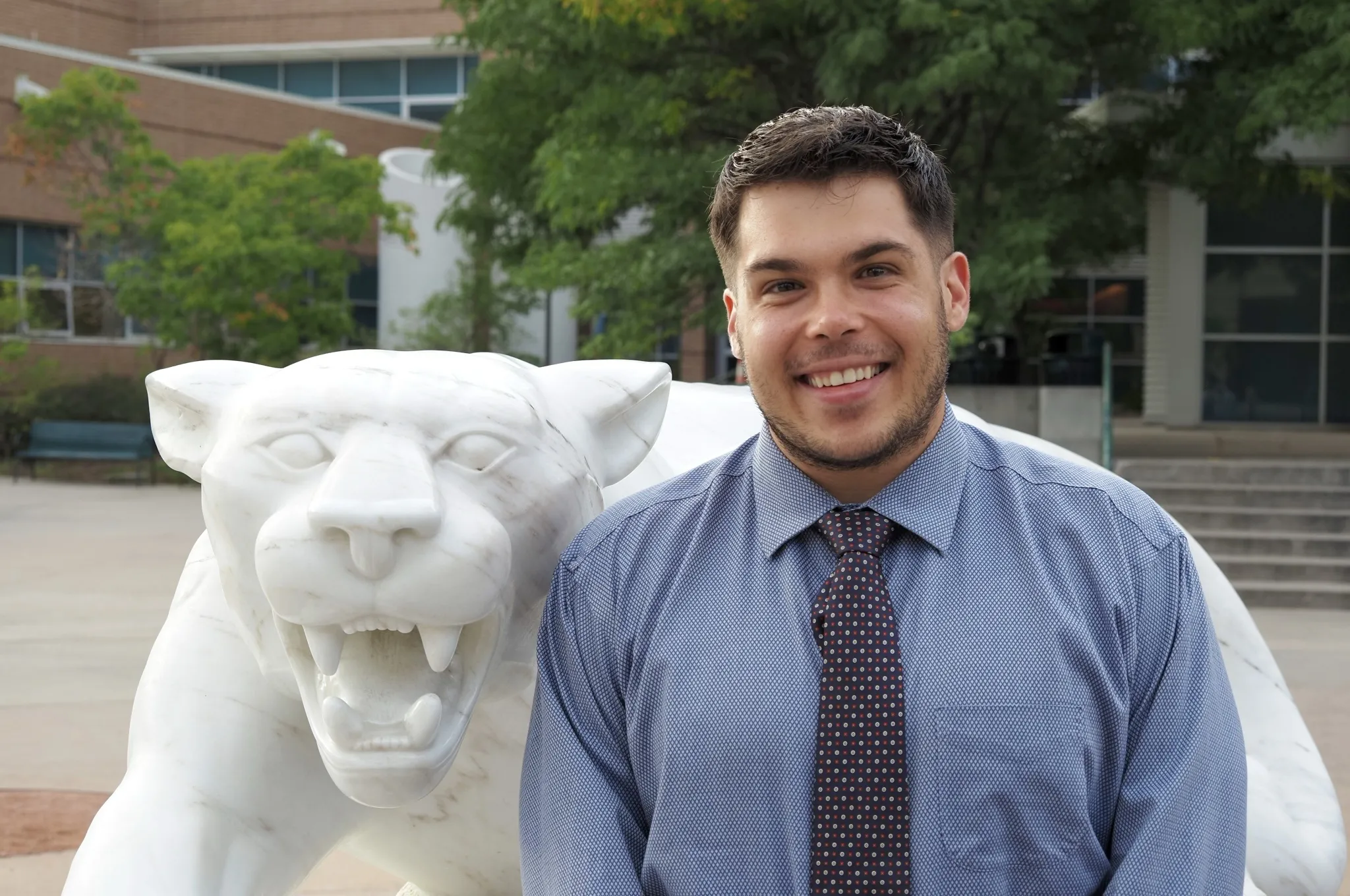 Photo of Jacks Pastuer posing next to a mountain lion statue